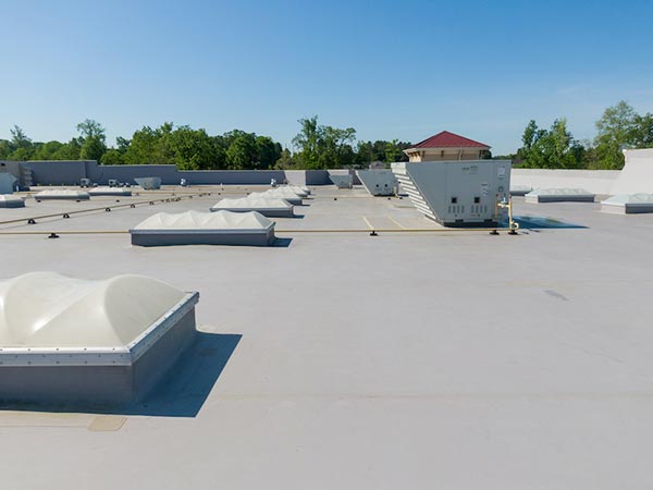 Flat-Roof-Installation-Stevens-Point-WI-Wisconsin-1 | Golden Eagle Roofing Flat commercial roof with multiple white domed skylights and HVAC units, blue sky and trees in the background.