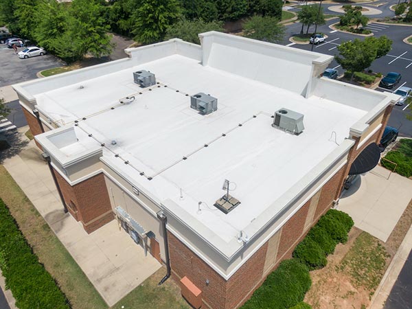 Flat-Roof-Installation-Stevens-Point-WI-Wisconsin-2 | Golden Eagle Roofing Aerial view of a flat white commercial roof with three rooftop HVAC units and string lights along the edge.